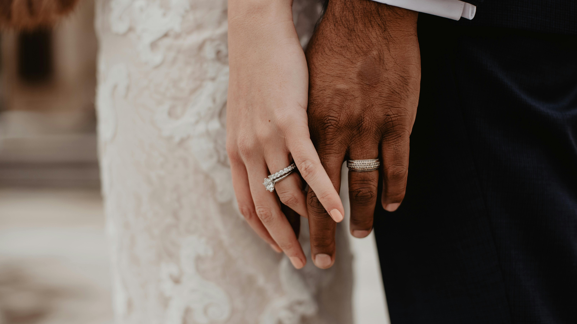 Bride and groom holding hands, showing diamond engagement ring and wedding band
